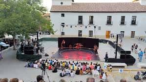 Evento cultural en la plaza con escenario montado y público sentado