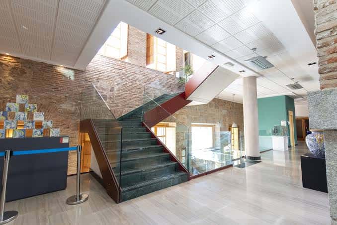 Ampio vestíbulo del Centro Cultural Rafael Morales con escalera de cristal y muros de ladrillo