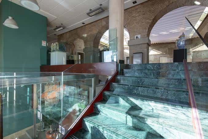 Escalera principal con pasamanos de vidrio y detalles arquitectónicos en ladrillo visto