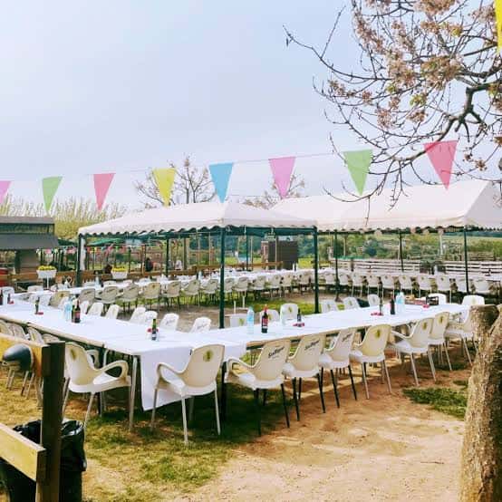 Salón al aire libre preparado para eventos con decoración colorida y mesas largas