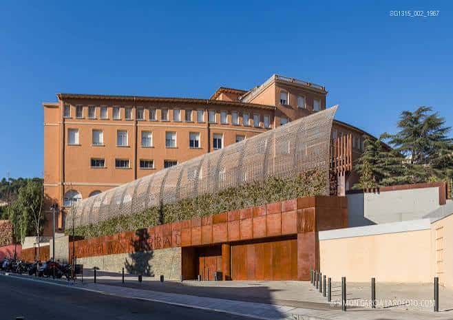 Vista exterior del edificio principal con fachada de ladrillo y estructura metálica curva