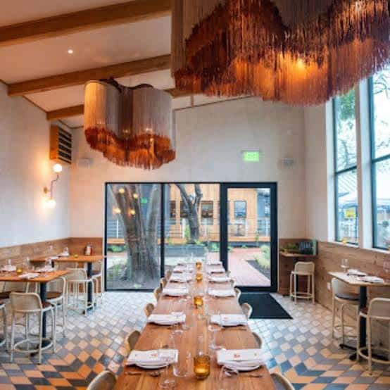 Sala principal del restaurante con lámparas decorativas y mesa larga preparada para evento