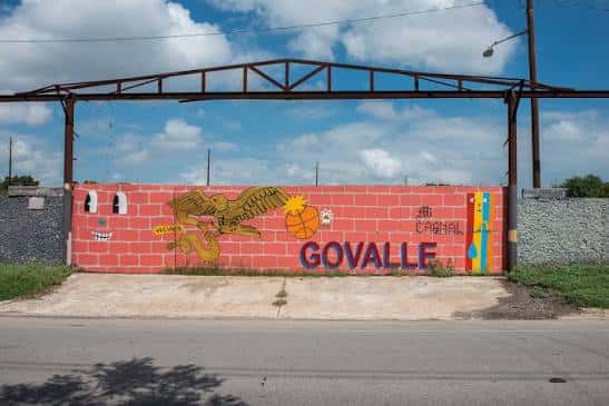 Muro de ladrillo rojo con murales coloridos y la palabra GOVALLE en Austin