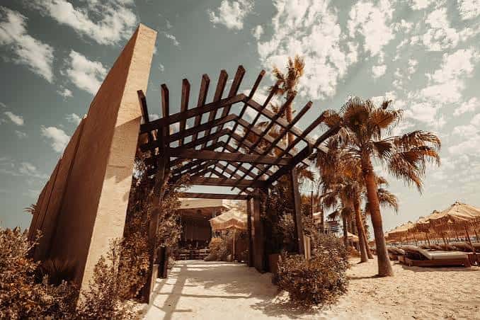 Entrada principal con estructura de madera y palmeras