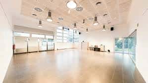Salón principal del Casal de Barri Can Rectoret con suelo de madera y grandes ventanales