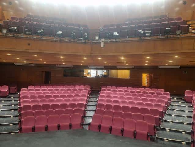 Plano amplio del salón de actos con asientos en gradas y techo acústico