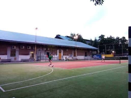 Jugadores practicando tenis en pista cubierta del centro deportivo