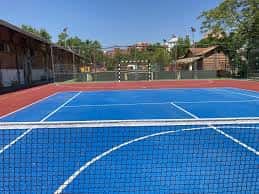 Pista de tenis azul con red en primer plano bajo cielo despejado