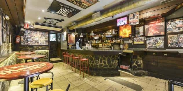 Espacio interior del bar con mesas redondas y ambiente acogedor