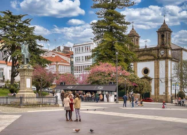 Plaza principal con iglesia histórica, estatua y personas disfrutando del ambiente