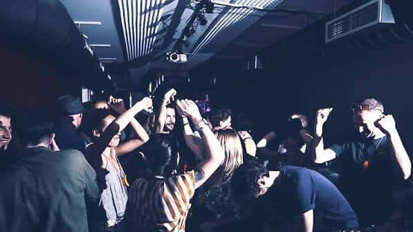 Pista de baile llena con personas celebrando bajo luces de club