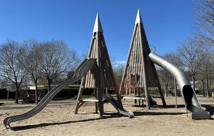 Zona de juegos infantiles con estructuras en forma de pirámide y toboganes metálicos