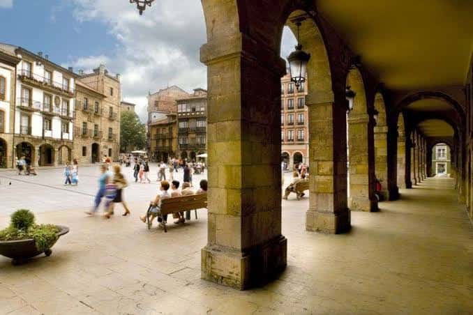 Vista desde los soportales hacia la Plaza Mayor con gente caminando