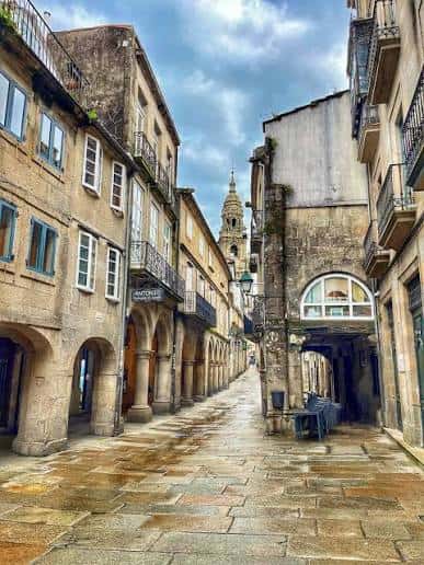 Calle empedrada con arcos y fachadas históricas bajo cielo nublado