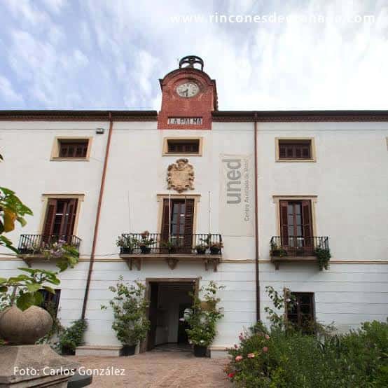 Vista frontal del edificio blanco con torre del reloj y balcones