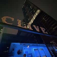 Fachada nocturna del local Clive con letrero luminoso