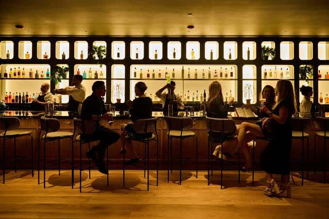 Interior del bar con barra iluminada y clientes sentados