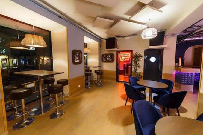 Interior del Tempo Audiophile Club con mesas y sillas azules