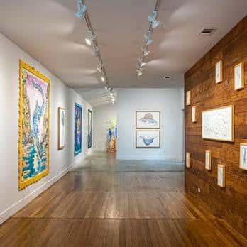 Interior de la galería con arte en las paredes y suelo de madera
