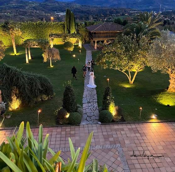 Ceremonia de boda al atardecer en el jardín iluminado del recinto