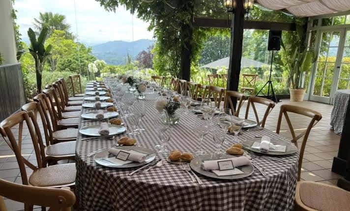 Mesa larga dispuesta en terraza con vista a la montaña y decoración rústica