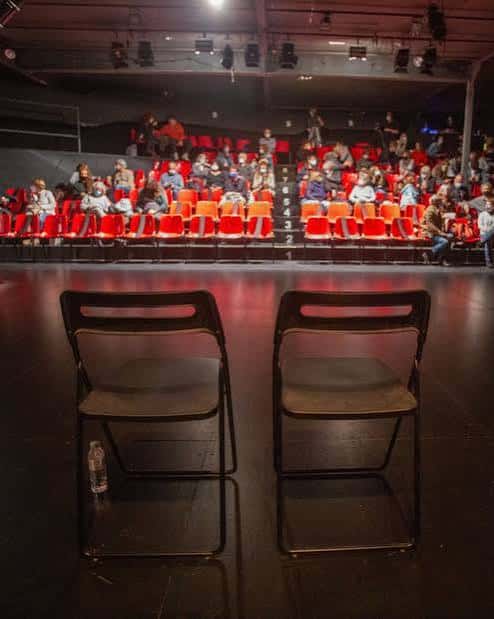 Interior del auditorio con público sentado en butacas rojas durante un evento