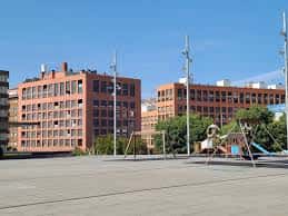 Plaza abierta con zona de juegos infantiles y fachadas de bloques de viviendas en Pamplona