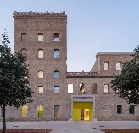 Fachada principal de La Farinera al atardecer, destacando la puerta amarilla y la arquitectura industrial restaurada