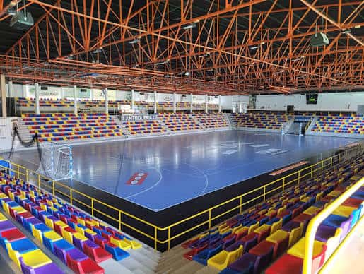 Vista interior del pabellón polideportivo con pista de baloncesto y gradas multicolores