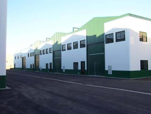 Fachada de nave industrial blanca y verde dentro del polígono