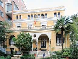 Fachada principal del edificio amarillo con balcones y entrada arqueada