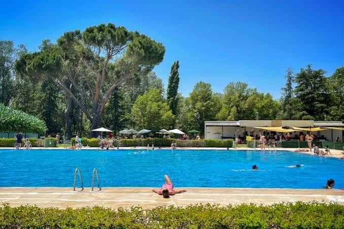 Vista amplia de la piscina del club con bañistas y zona de descanso bajo sombrillas