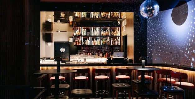 Interior del bar con barra iluminada y techo estrellado
