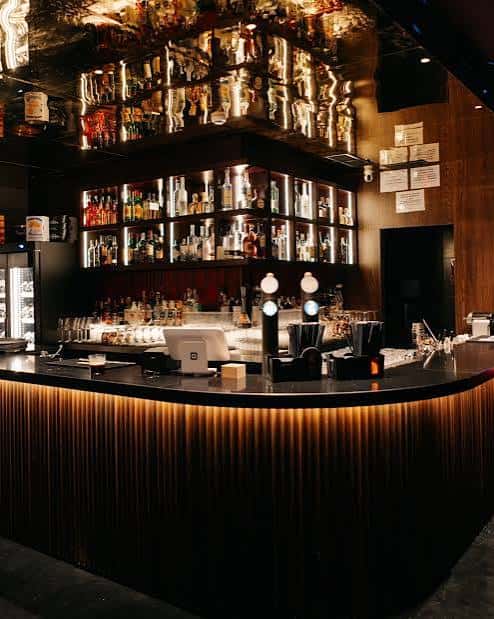 Vista de la barra principal con estantería de botellas y diseño moderno