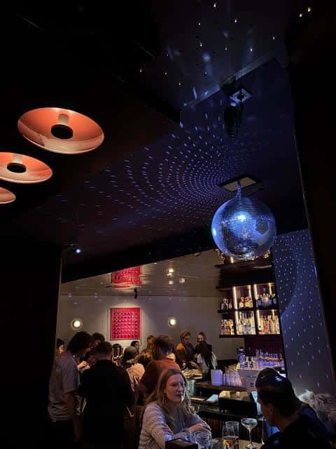 Ambiente nocturno con gente disfrutando bajo bola de discoteca