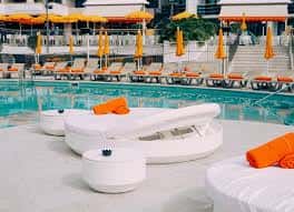 Zona de relax junto a la piscina con sofás blancos y toallas naranjas