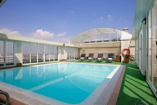 Piscina exterior en la azotea con vistas a la ciudad y tumbonas