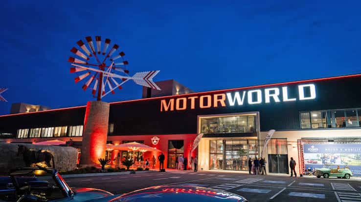 Fachada nocturna de Motorworld Mallorca con iluminación y molino decorativo
