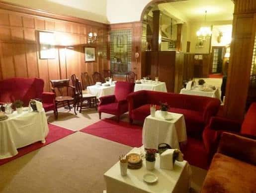 Interior elegante del Club Cantábrico con mesas dispuestas para cena y sofás rojos