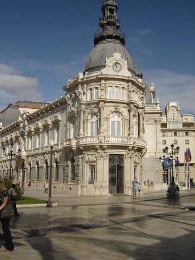 Vista lateral del palacio mostrando la torre con reloj y banderas institucionales