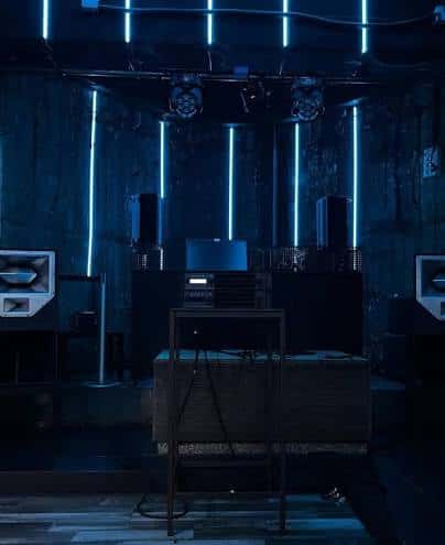 Escenario del club con iluminación azul y equipo de DJ