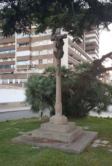 Crucero de piedra en un jardín junto a edificios residenciales