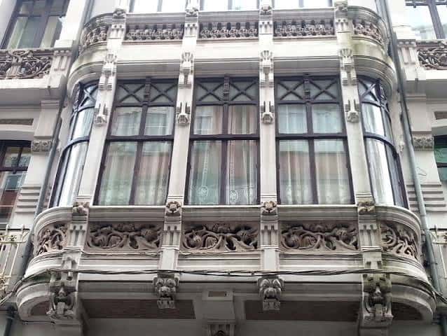 Detalle arquitectónico de balcón modernista con ornamentación en hierro y piedra