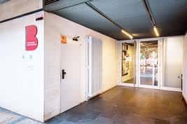 Entrada moderna del Casal de Barri Espai Antoni Miró Peris con fachada blanca y puerta de cristal