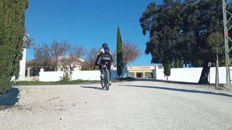 Ciclista acercándose a la entrada de Viña La Canareira en Hijuela del Carrascal