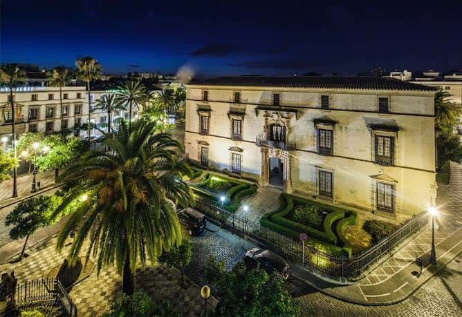 Vista nocturna del Palacio Domecq con fachada iluminada y jardines