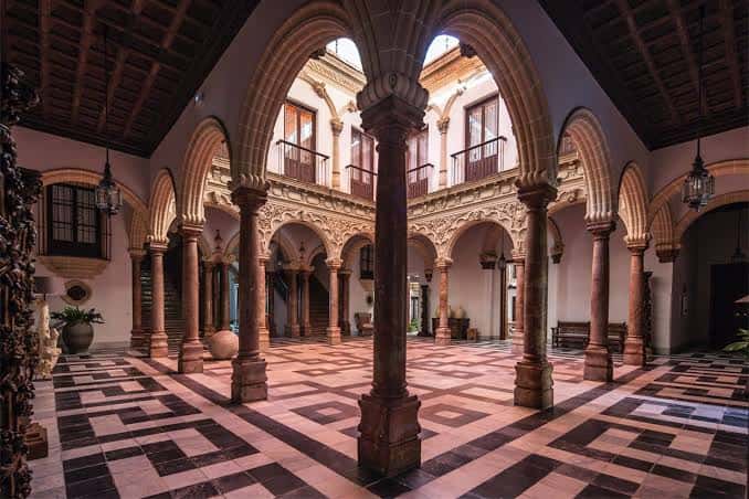 Patio interior de arcos y columnas con suelo de baldosas geométricas