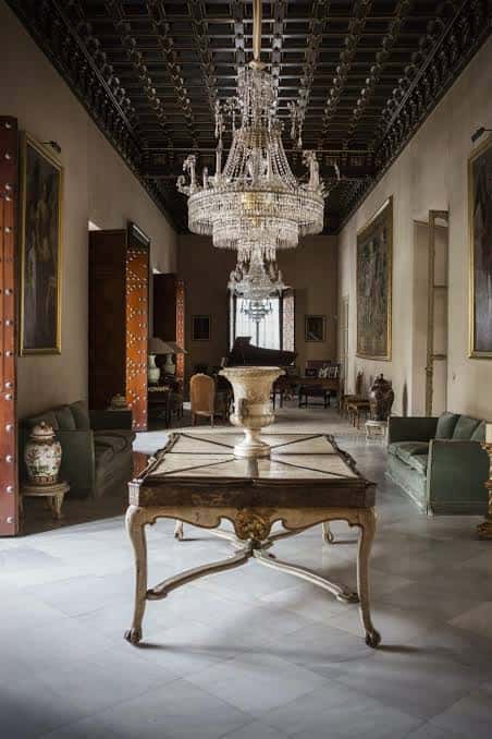 Galería elegante con lámpara de cristal, cuadros y sofás verdes