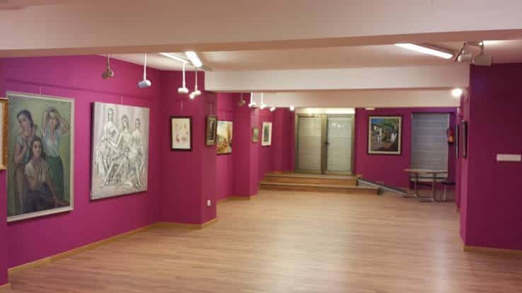 Sala interior del centro con paredes moradas, obras de arte y suelo de madera