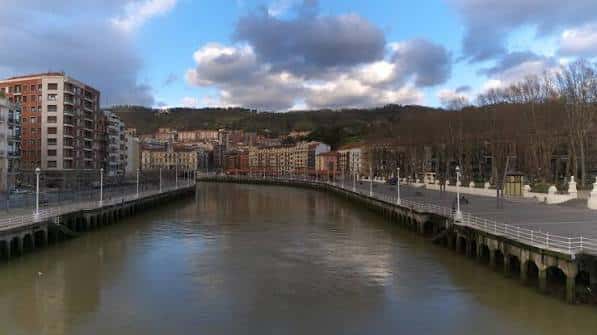 Paseo fluvial junto al río Nervión con edificios de Bilbao al fondo